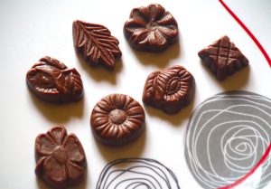 7 pieces of walnut fudge on a white plate with circular designs.