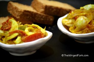 Boiled egg chilly fry in two white bowls in front of some toast for final step of serving the boiled egg chilly fry with toast or bread