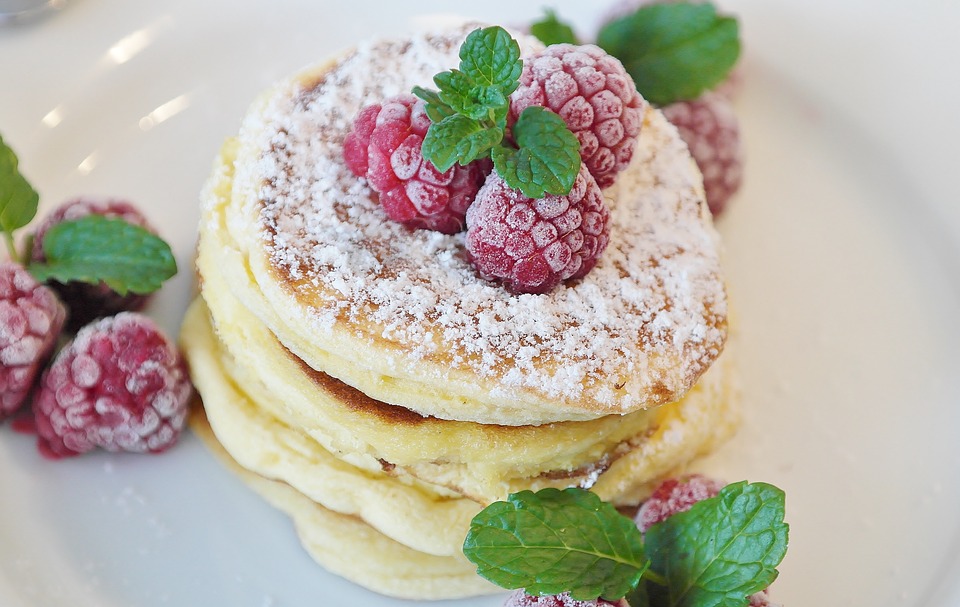Pancakes with berries and sugar dust on top.