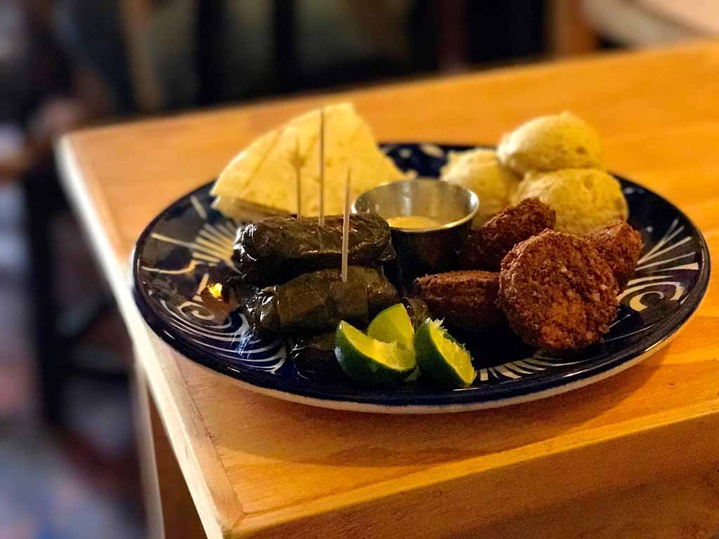Plate filled with crispy falafel, smooth hummus and filling stuffed vine leaves.