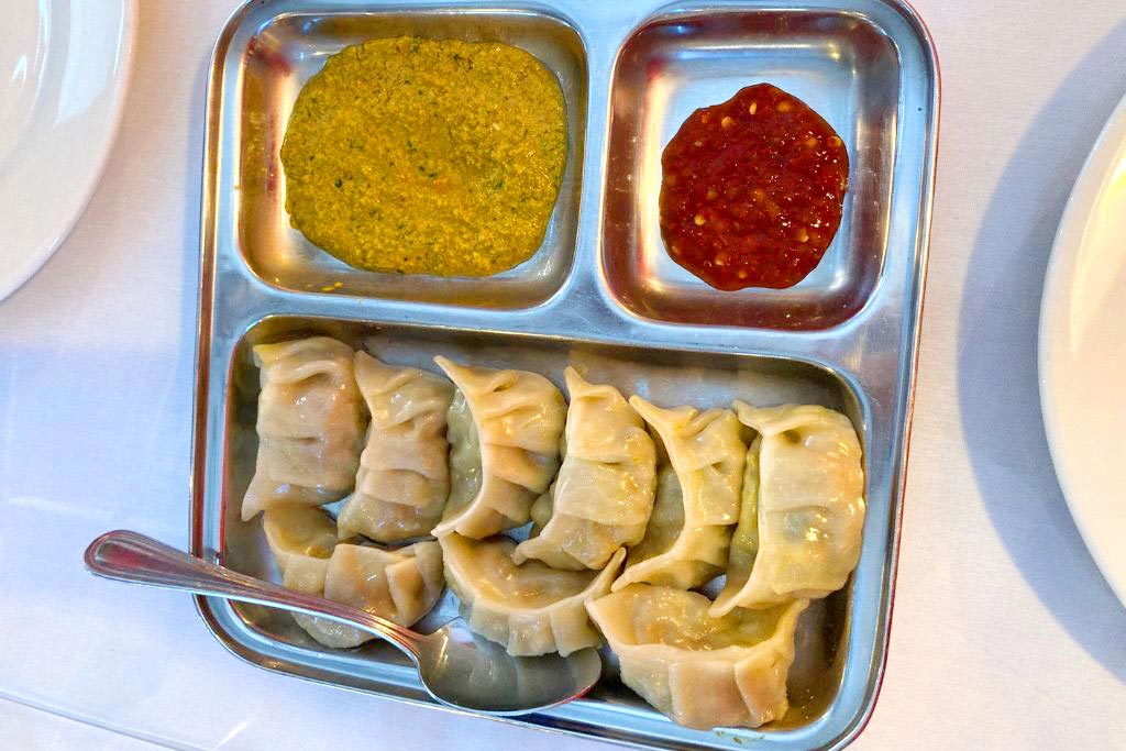 Shangrila Himalayan Kitchen chicken momos and chutney in a steel plate