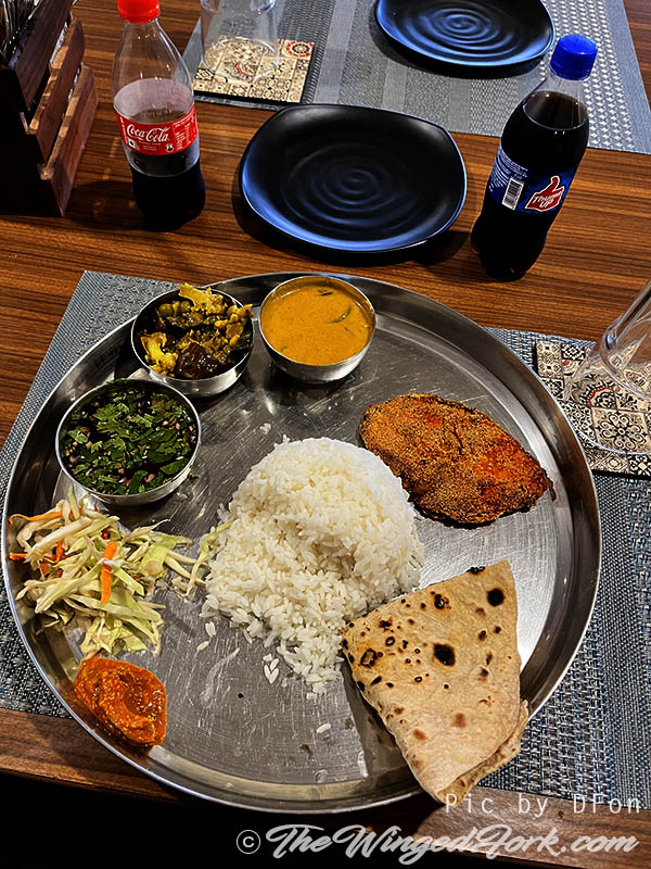 Fish thali platter on a wooden table.