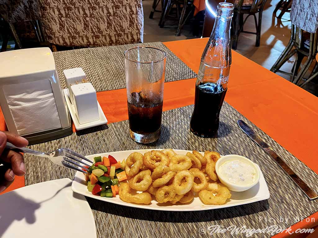 Squid rings on a platter next to rum and coke.