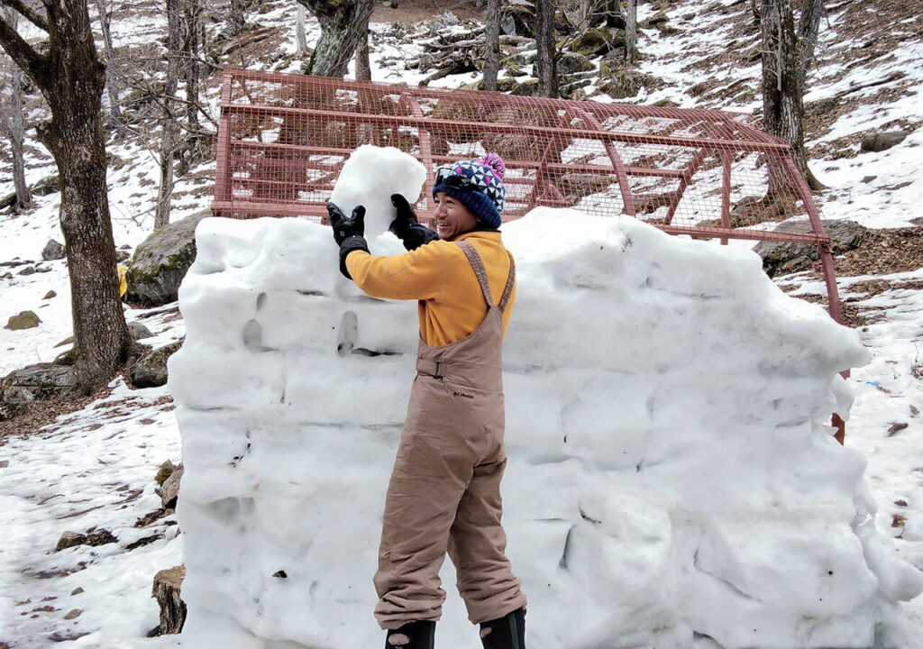 Man placing ice blocks on igloo.