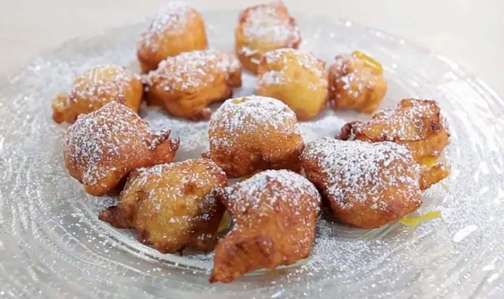 Small deep fried balls with sprinkled powdered sugar.