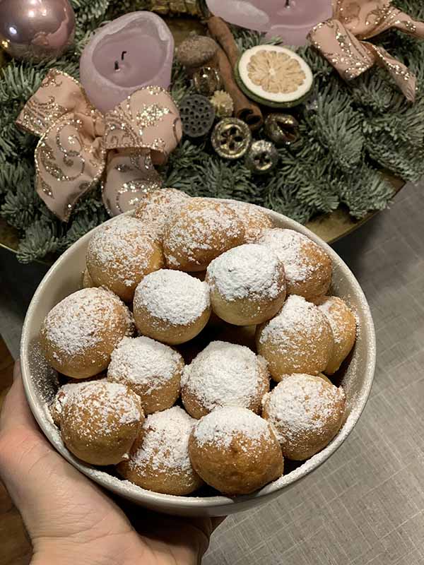 Small, fried doughnut-like pastries with powdered sugar in a bowl.