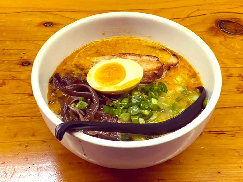 Ramen with eggs and veggies served in an bowl.